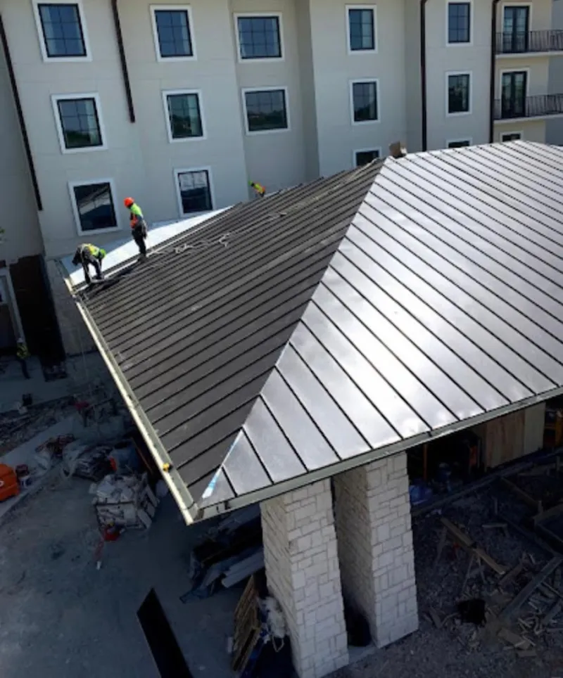 Crew installing standing seam metal roof panels on a commercial project in Clyde